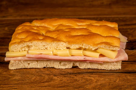 sandwich with salami and vegetables on a wooden surfaceの写真素材