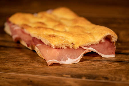 sandwich with salami and vegetables on a wooden surfaceの写真素材
