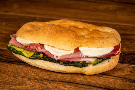 sandwich with salami and vegetables on a wooden surfaceの写真素材