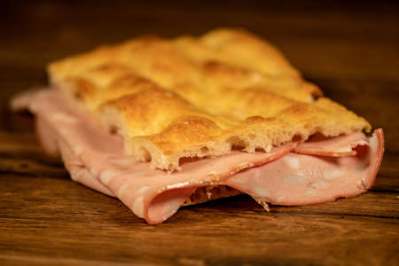 sandwich with salami and vegetables on a wooden surfaceの写真素材