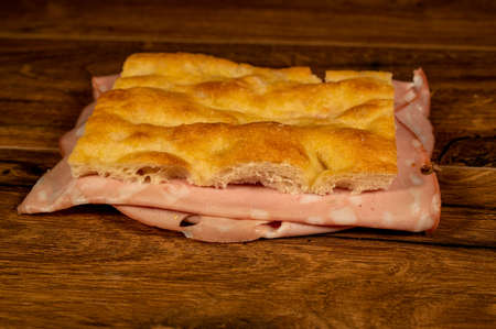 sandwich with salami and vegetables on a wooden surfaceの写真素材