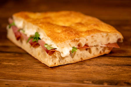 stuffed focaccia with cold cuts and vegetables on a wooden surfaceの写真素材