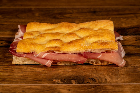 stuffed focaccia with cold cuts and vegetables on a wooden surfaceの写真素材