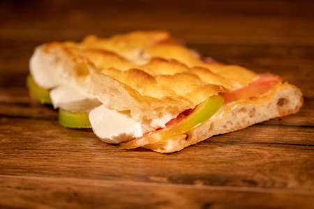 stuffed focaccia with cold cuts and vegetables on a wooden surfaceの写真素材