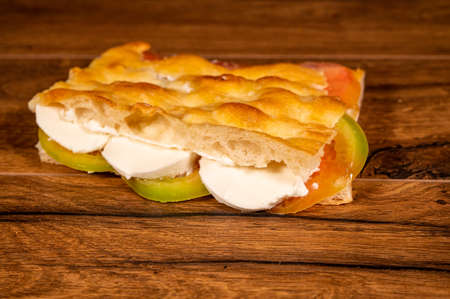 stuffed focaccia with cold cuts and vegetables on a wooden surfaceの写真素材
