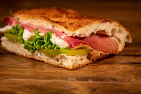 stuffed focaccia with cold cuts and vegetables on a wooden surfaceの写真素材