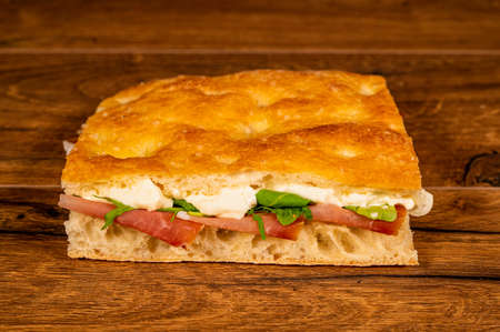 stuffed focaccia with cold cuts and vegetables on a wooden surfaceの写真素材