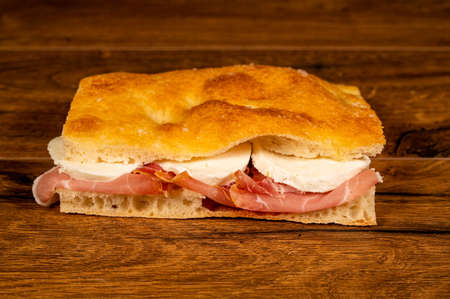 stuffed focaccia with cold cuts and vegetables on a wooden surfaceの写真素材