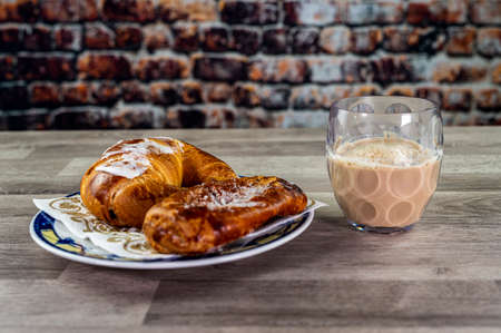 brioche with glass of milk and coffee on wooden surfaceの写真素材