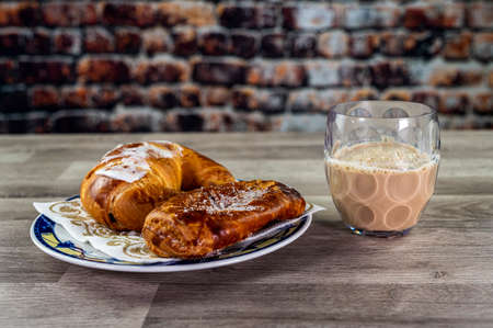 brioche with glass of milk and coffee on wooden surfaceの写真素材