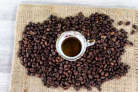 cup of coffee amidst coffee beans on wooden topの写真素材