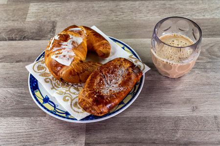 brioche with glass of milk and coffee on wooden surfaceの写真素材