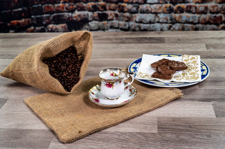 cup of coffee with coffee grains and biscuits on wooden surfaceの写真素材