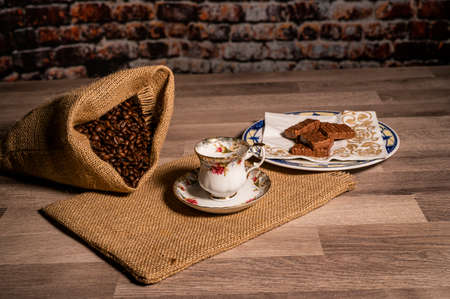 cup of coffee with coffee grains and biscuits on wooden surfaceの写真素材