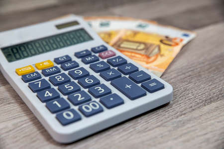 50 euro banknotes with calculator on wooden table