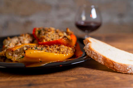 plate of peppers au gratin on wooden table set with cutlery and glass of wineの写真素材