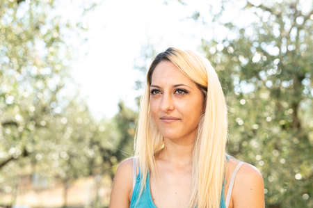 blonde girl in the countryside serious expression on nature backgroundの写真素材