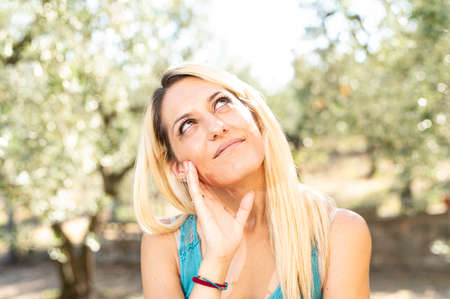 blonde girl in the countryside serious expression on nature backgroundの写真素材