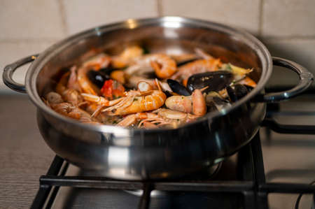 fish soup in the pan with wood mixture during cookingの写真素材