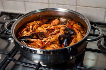 fish soup in the pan with wood mixture during cookingの写真素材