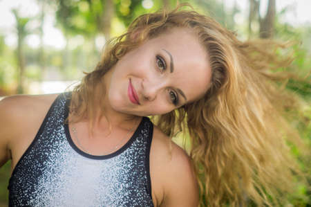 Blond girl, wears sportswear and does exercise in the garden. Natural and with tennis racket. He enjoys making gestures and curious and very original expressions. Young, beautiful and sexy.の写真素材