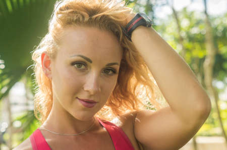 Blond girl, wears sportswear and does exercise in the garden. Natural and with tennis racket. He enjoys making gestures and curious and very original expressions. Young, beautiful and sexy.の写真素材