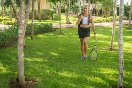 Blond girl, wears sportswear and does exercise in the garden. Natural and with tennis racket. He enjoys making gestures and curious and very original expressions. Young, beautiful and sexy.の写真素材