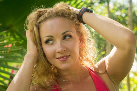 Blond girl, wears sportswear and does exercise in the garden. Natural and with tennis racket. He enjoys making gestures and curious and very original expressions. Young, beautiful and sexy.の写真素材