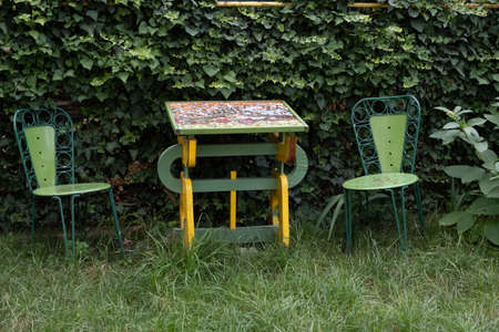 One wood vintage table with mosaic and 2 beautiful chairs in the gardenの写真素材