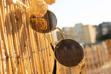 Vintage sunglasses round lens model hanging on a babmboo fence. Selective focusの写真素材