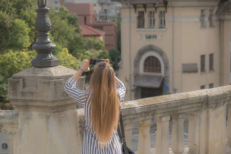 Beautiful girl with long hair making pictures with her phone. Selective focus