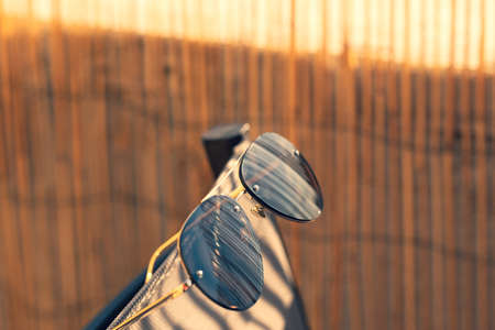 Aviator Sunglasses model with big black lenses for men reflecting the sun in a summer day closeup . Selective focusの写真素材