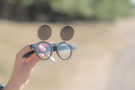 Black steampunk sunglasses with round lenses flip up retro model close up shoot in a summer day....