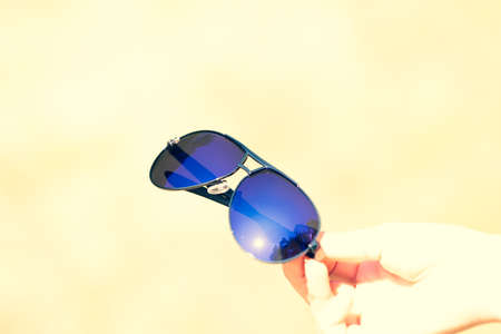 Retro aviator sunglasses model hold by hand in a summer day closeup . Selective focusの写真素材