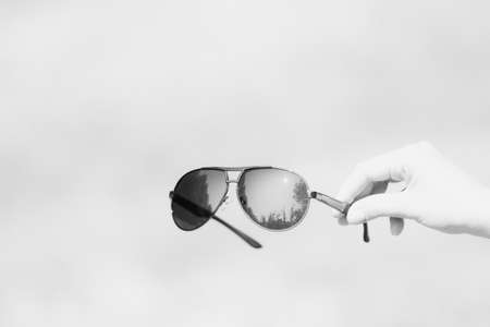 Retro aviator sunglasses model hold by hand in a summer day closeup . Selective focusの写真素材