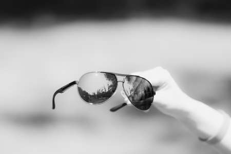 Retro aviator sunglasses model hold by hand in a summer day closeup . Selective focusの写真素材