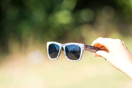 Retro sunglasses model with black lenses hold by hand closeup. Selective focusの写真素材