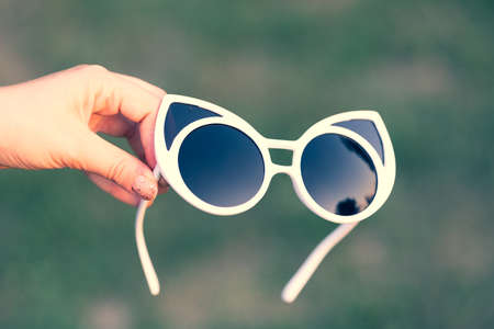 Cat eye sunglasses hold by hand shoot outside closeup. Selective focusの写真素材