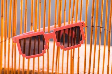 Pink pixel sunglasses model with black lenses closeup in a summer day. Selective focus