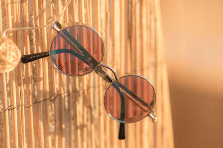 Steampunk sunglasses model with round lenses hanging on a bamboo fence in a summer day closeup. Selective focusの写真素材
