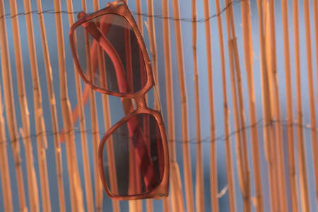 Classic sunglasses model hanging on a bamboo fence shoot in a summer day closeup. Selective focusの写真素材