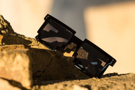 Black pixel sunglasses with black lenses closeup in a sunny day. Selective focus