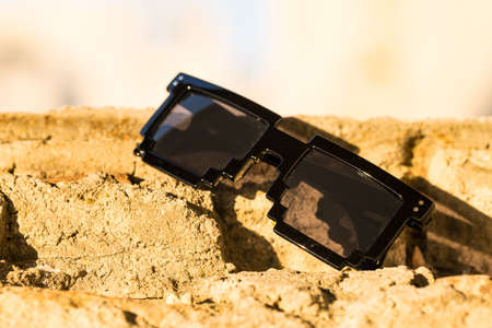 Black pixel sunglasses with black lenses closeup in a sunny day. Selective focus