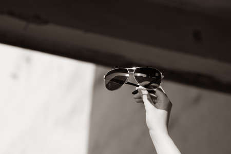Aviator Sunglasses model with big black lenses for men in a summer day hold by hand . Selective focusの写真素材