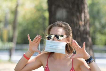 The girl wearing futuristic sunglasses and wearing a mask during the pandemic in a summer dayの写真素材