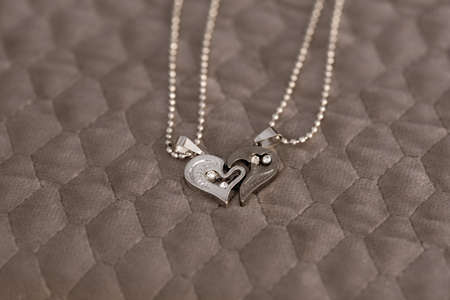 Couple set pendant necklace half of heart shoot outdoors in a sunny day closeup. Selective focus