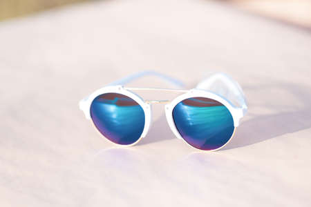 Retro sunglasses model with blue round lenses shoot outside in a sunny day closeup . Selective focusの写真素材
