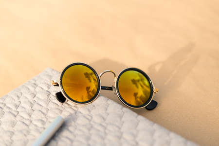 Sunglasses with golden round lenses shoot outside in a summer day closeup. Selective Focusの写真素材