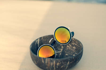 Sunglasses with golden round lenses shoot outside in a summer day closeup. Selective Focusの写真素材
