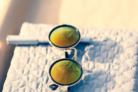 Sunglasses with golden round lenses shoot outside in a summer day closeup. Selective Focusの写真素材